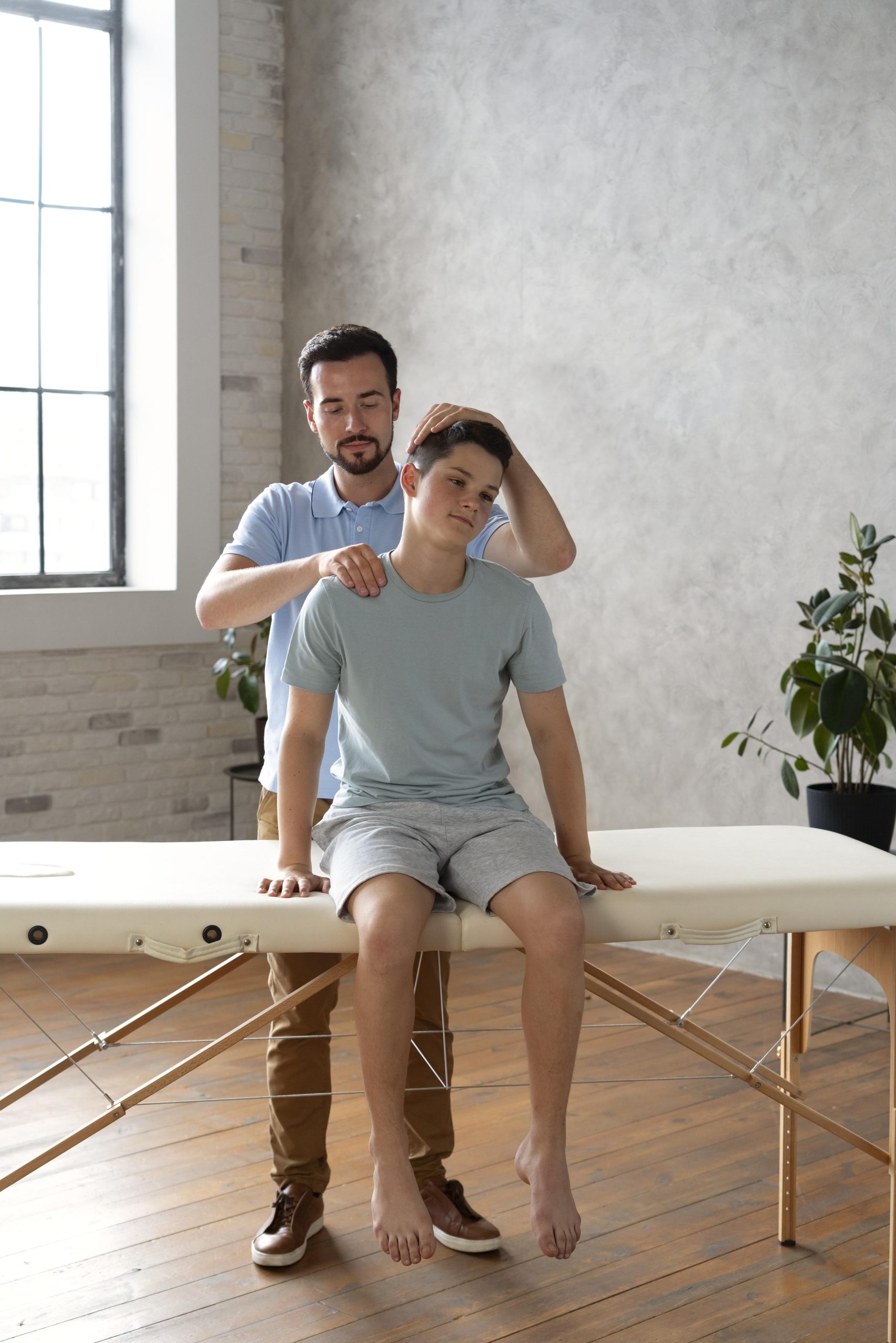 Physiotherapist helping a young patient with neck and shoulder mobility exercise